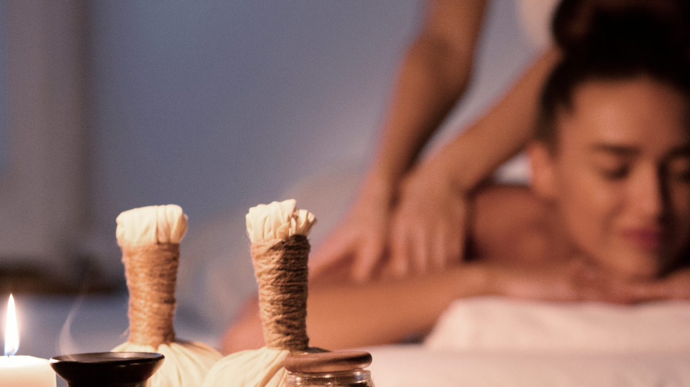A woman is getting a massage in a spa with candles in the background.