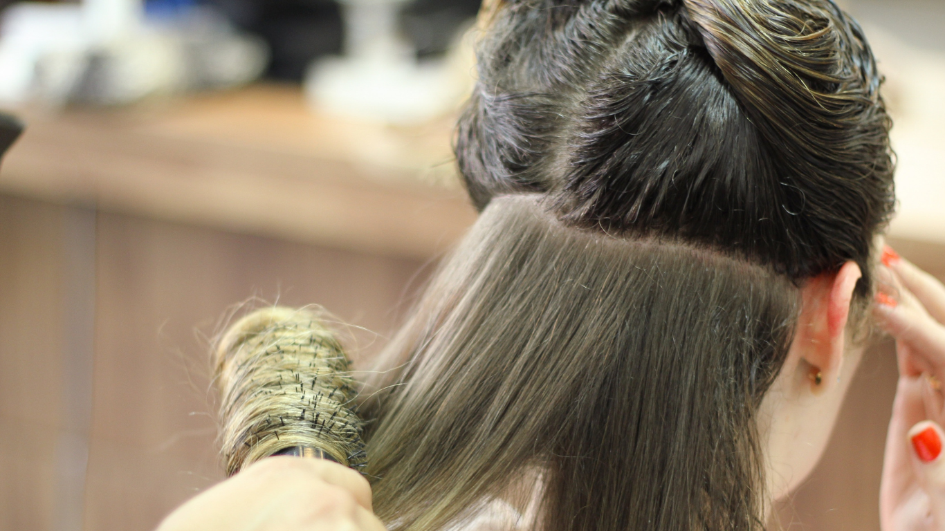 A woman is getting her hair blow dried by a hairdresser.