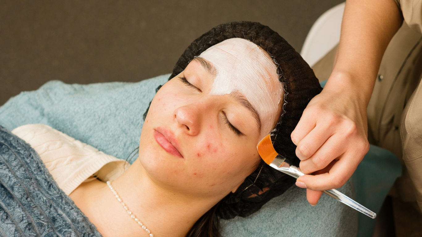 A woman is getting a facial treatment with a brush on her face.