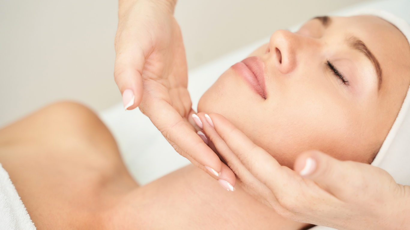 A woman is getting a facial massage at a spa.