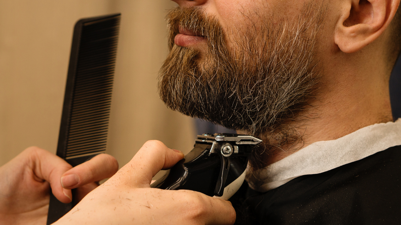 A man is getting his beard trimmed by a barber.