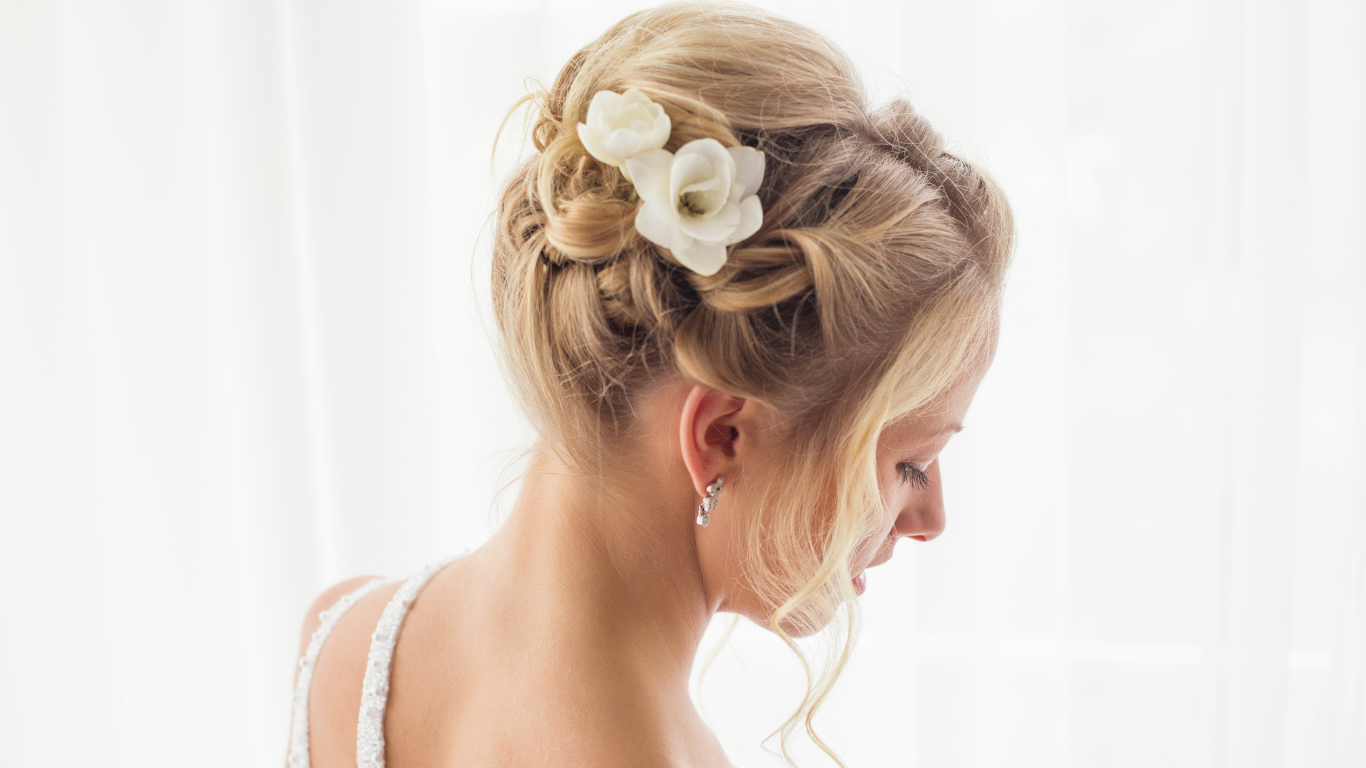 A woman with a flower in her hair is wearing a wedding dress.