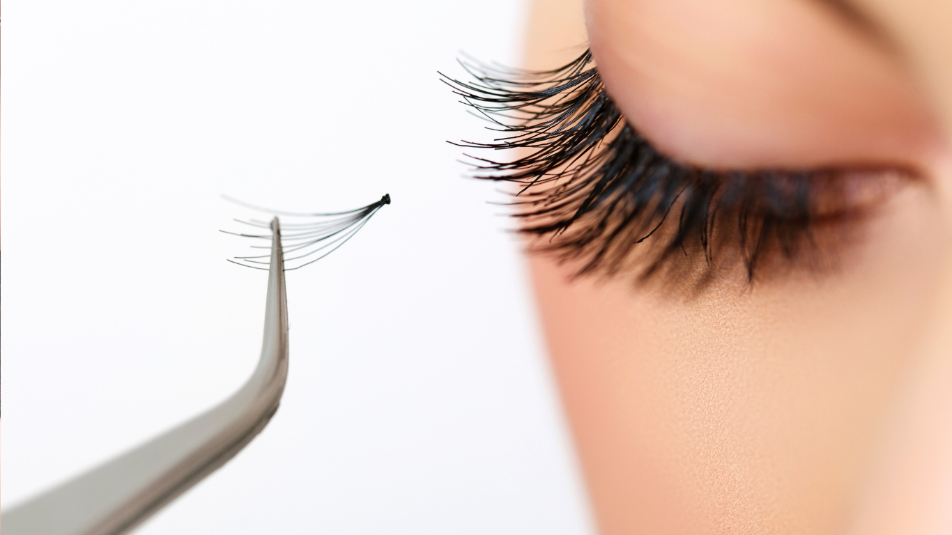 A close up of a woman 's eye with a pair of tweezers next to it.