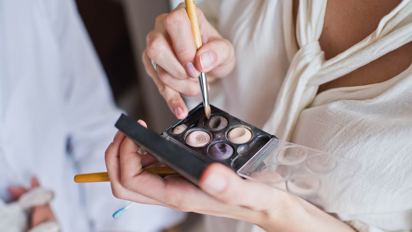 A woman is applying eye shadow to her eyes with a brush.