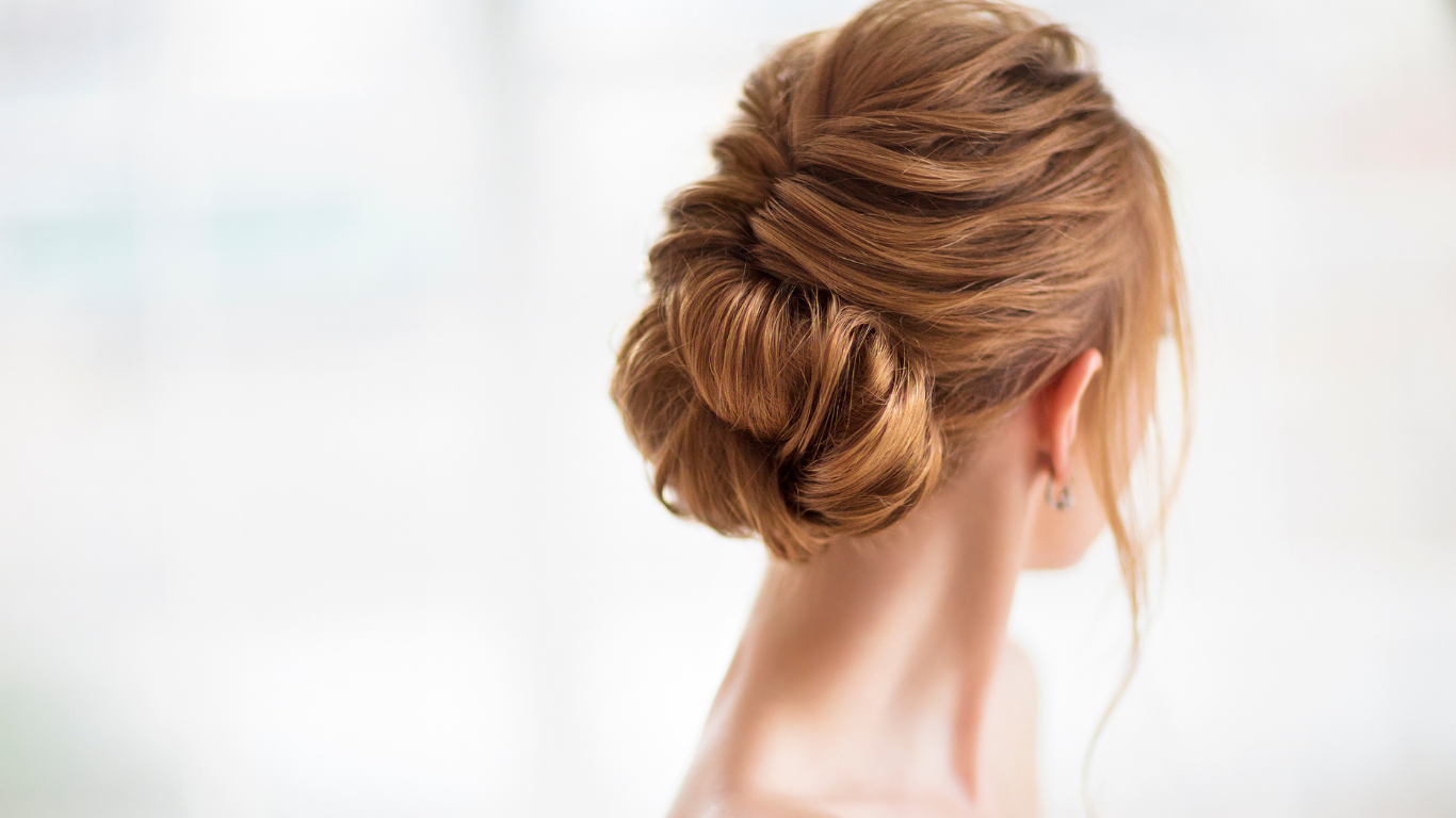 A woman is wearing her hair in a bun.