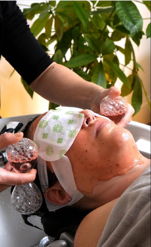 A woman is getting a facial treatment in a salon.