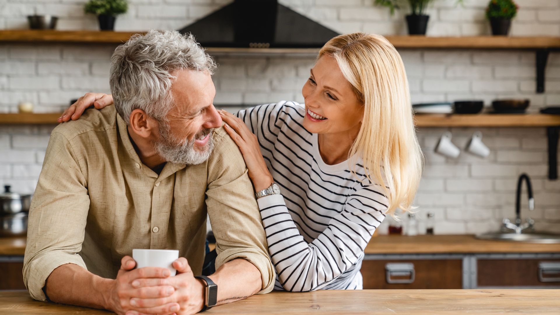 A man and a woman are sitting at a table in a kitchen looking at each other.