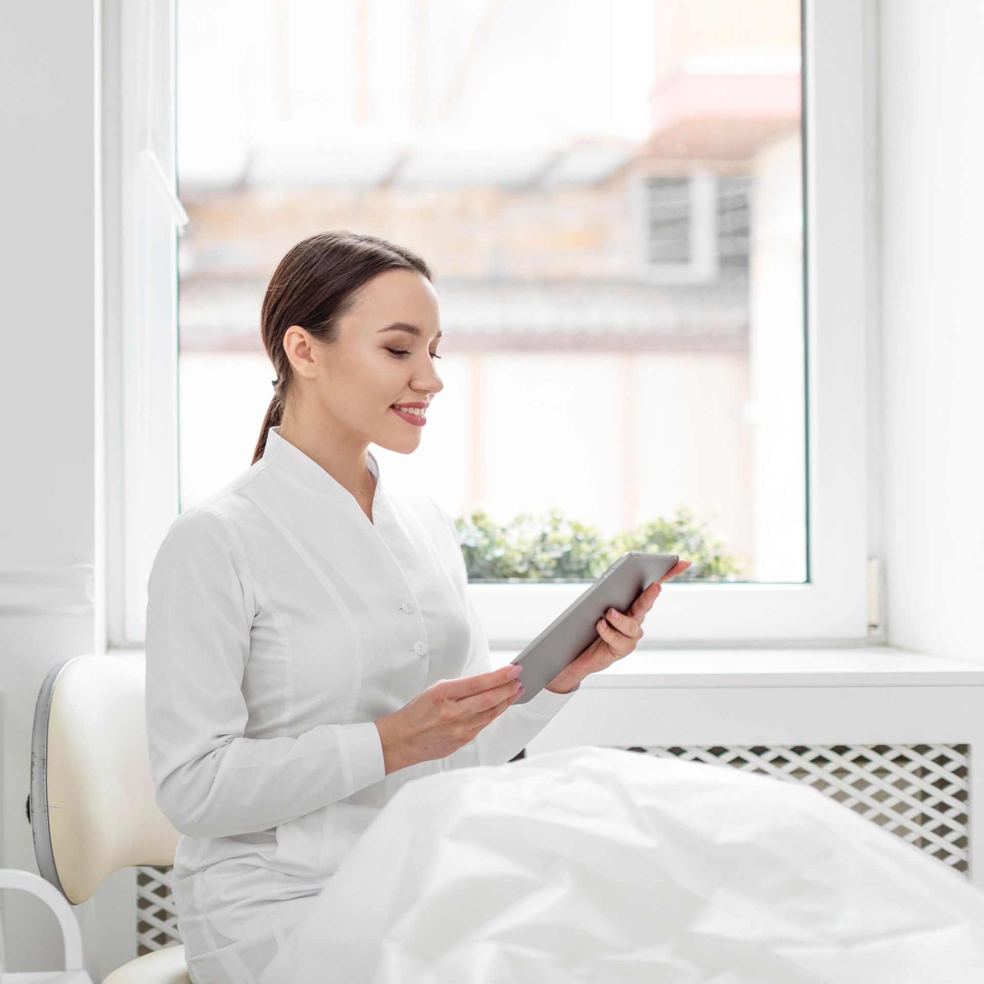 A woman in a bathrobe is sitting in a chair talking on a cell phone while receiving IV therapy infusion.