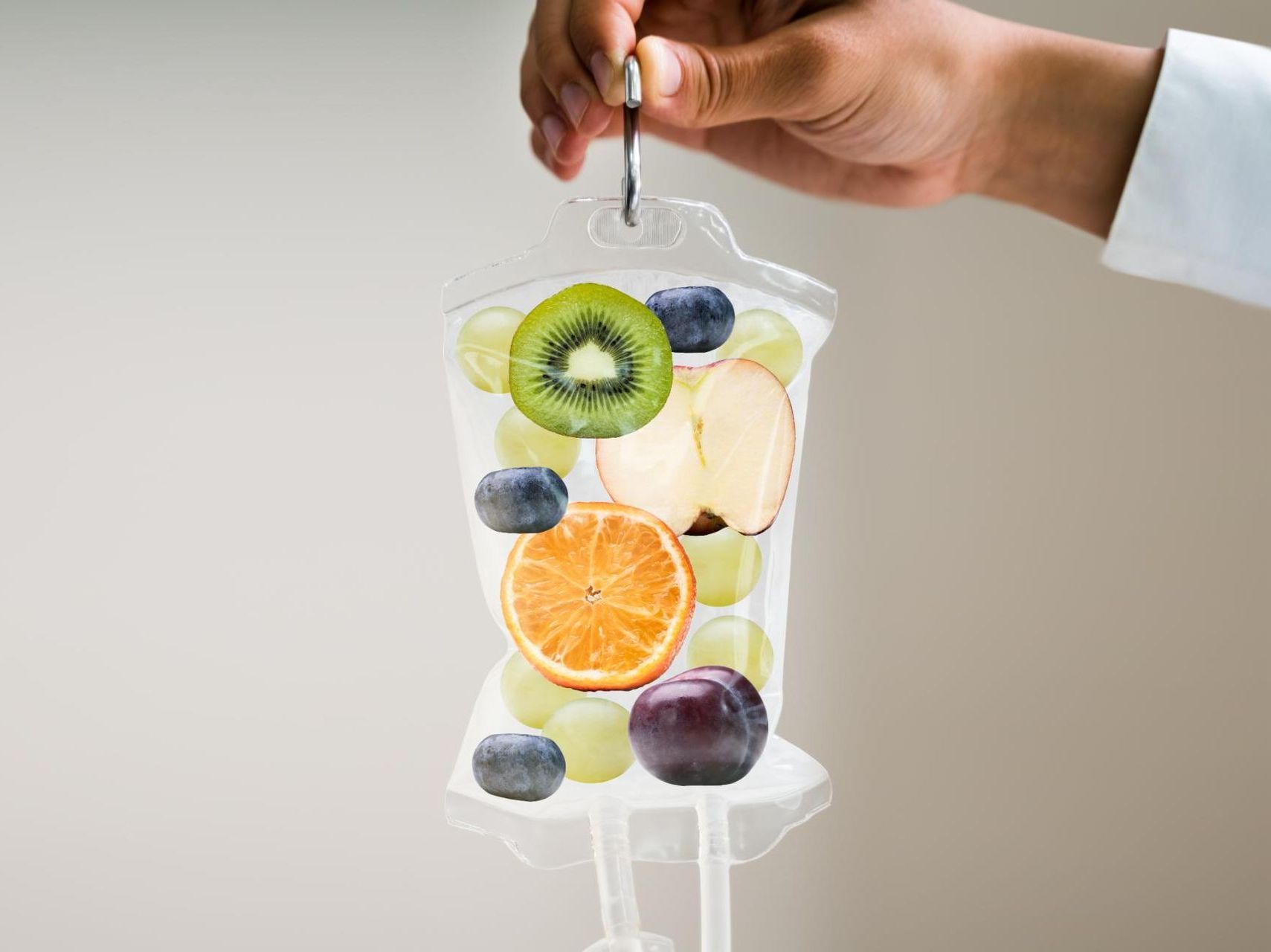 a person's hand holding IV bag with fruit