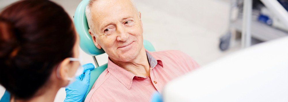 Older man doing an implant denture followup appointment