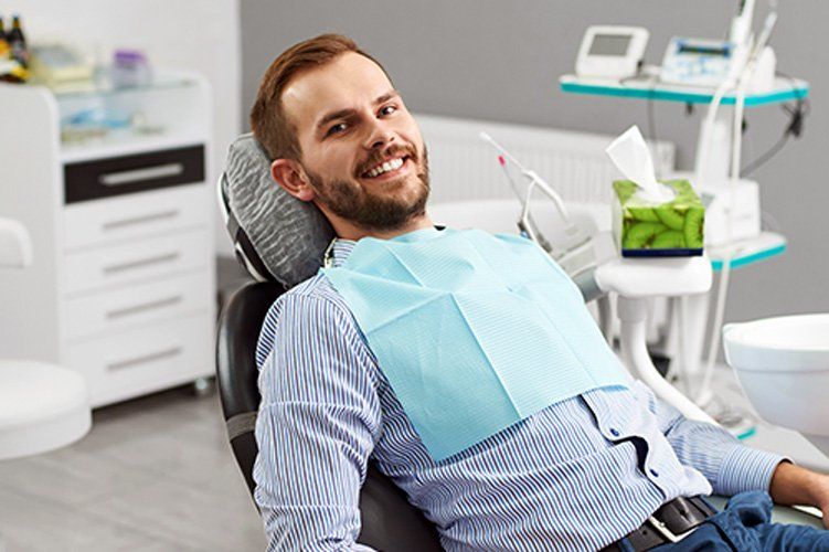 A man is smiling while sitting in a dental chair.