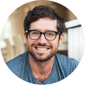 A man wearing glasses and a blue shirt smiles for the camera