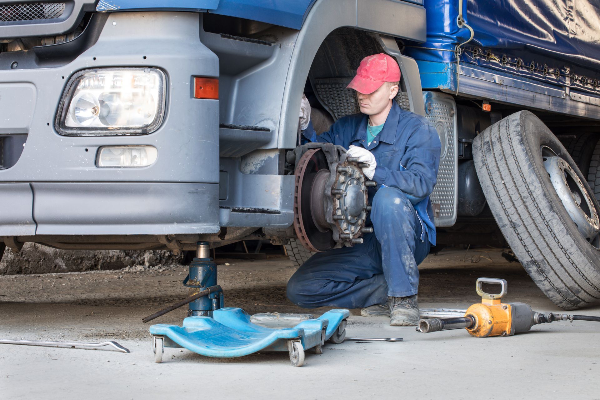 A technician is repairing a heavy-duty truck trailer brake assembly during maintenance.