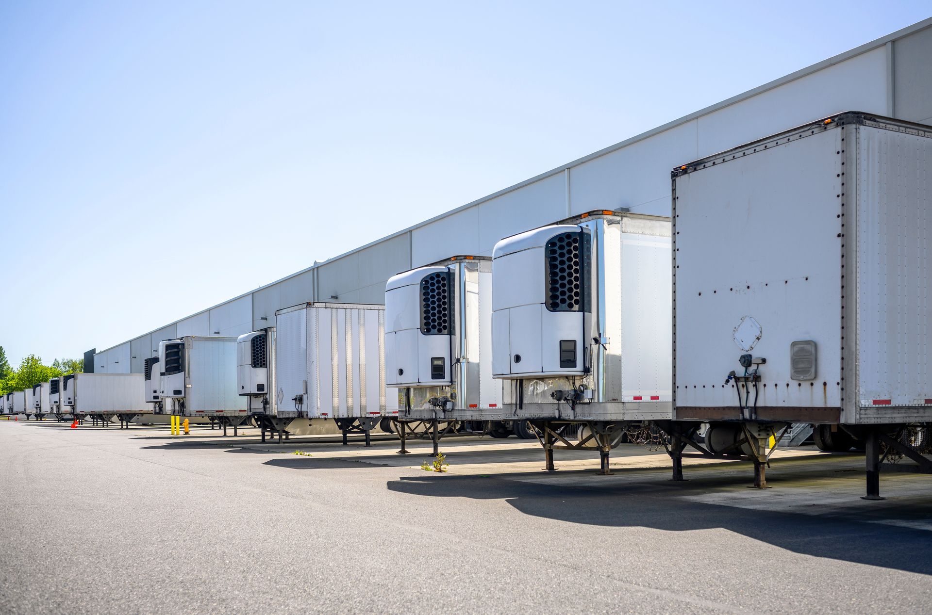Row of semi truck trailers lined up at a warehouse loading dock.