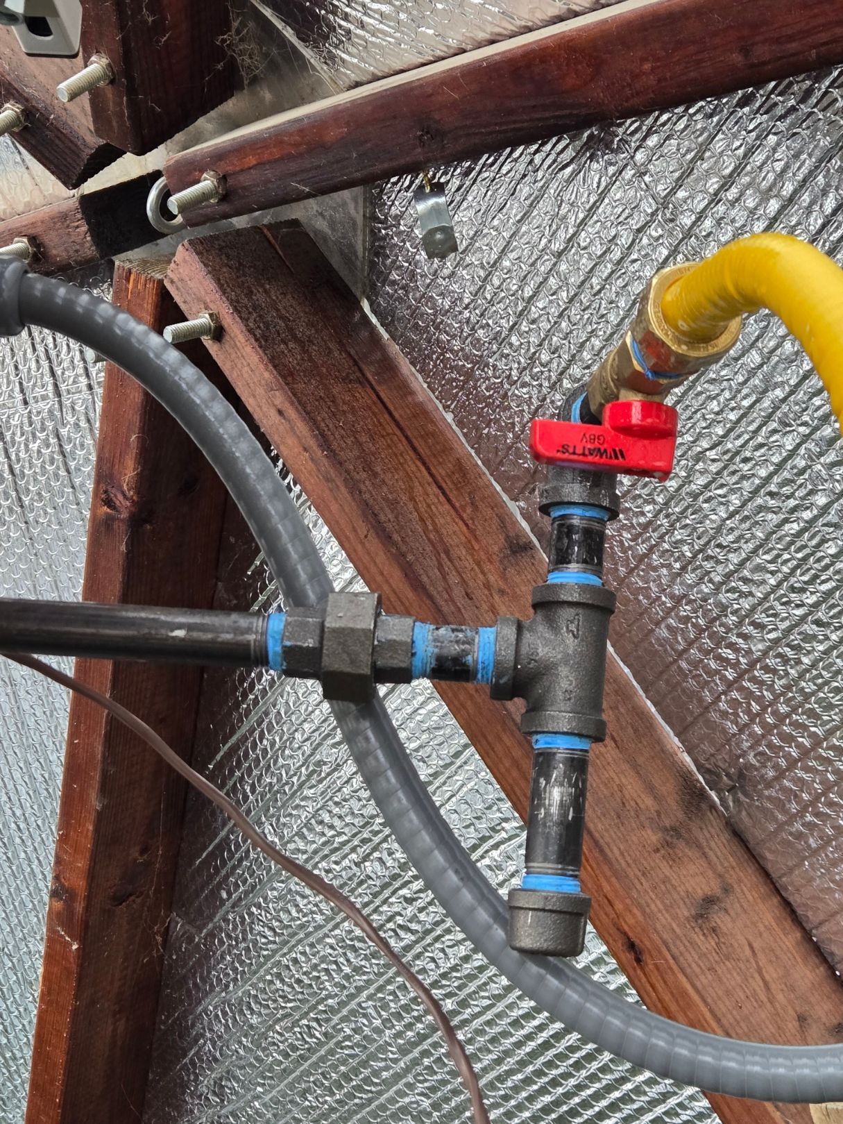 A person in work clothes installs a water heater on a white wall.