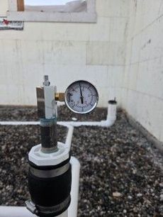 Pressure gauge on a water pipe, showing a reading of approximately 3 PSI.