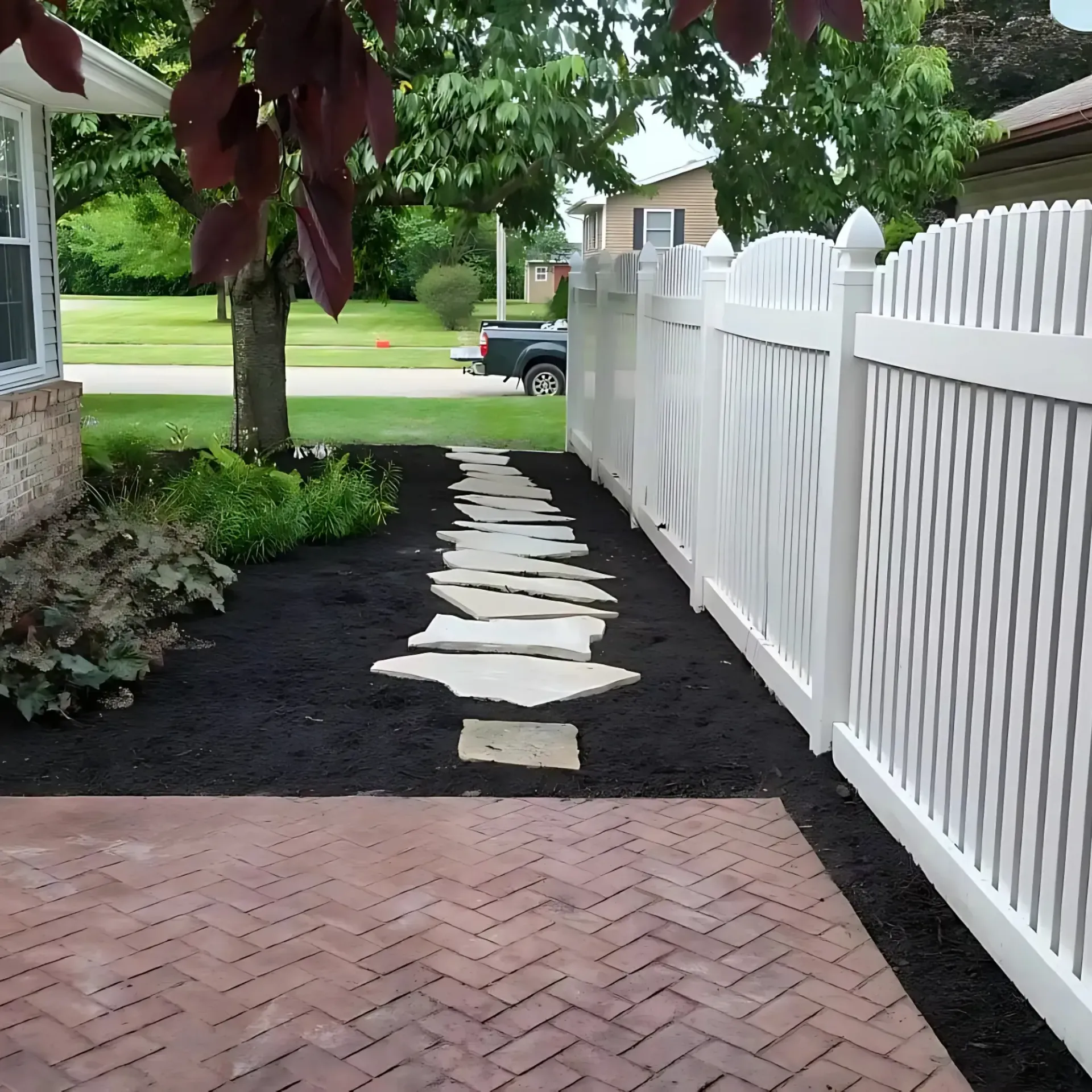 Green Wave Lawn Care - A lush green lawn with trees and bushes in the background