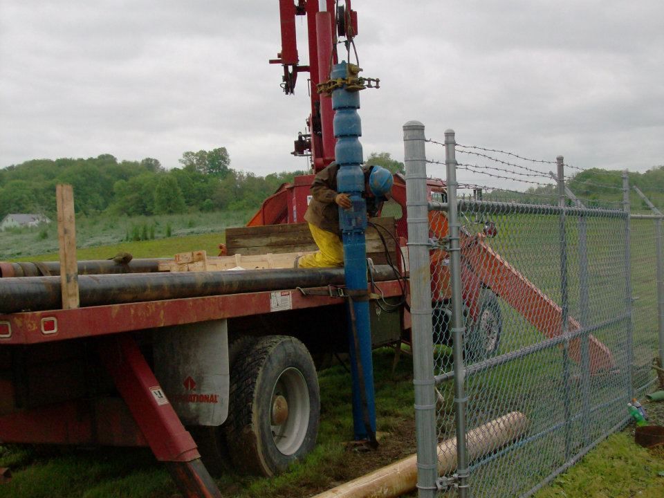 A Man Is Working on A Water Pump on The Back of A Truck - Liverpool, PA - Modern Pump & Equipment Inc
