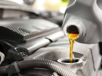 A bottle of oil is being poured into a car engine.