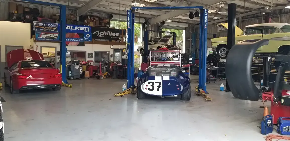 A couple of cars are sitting on a lift in a garage.