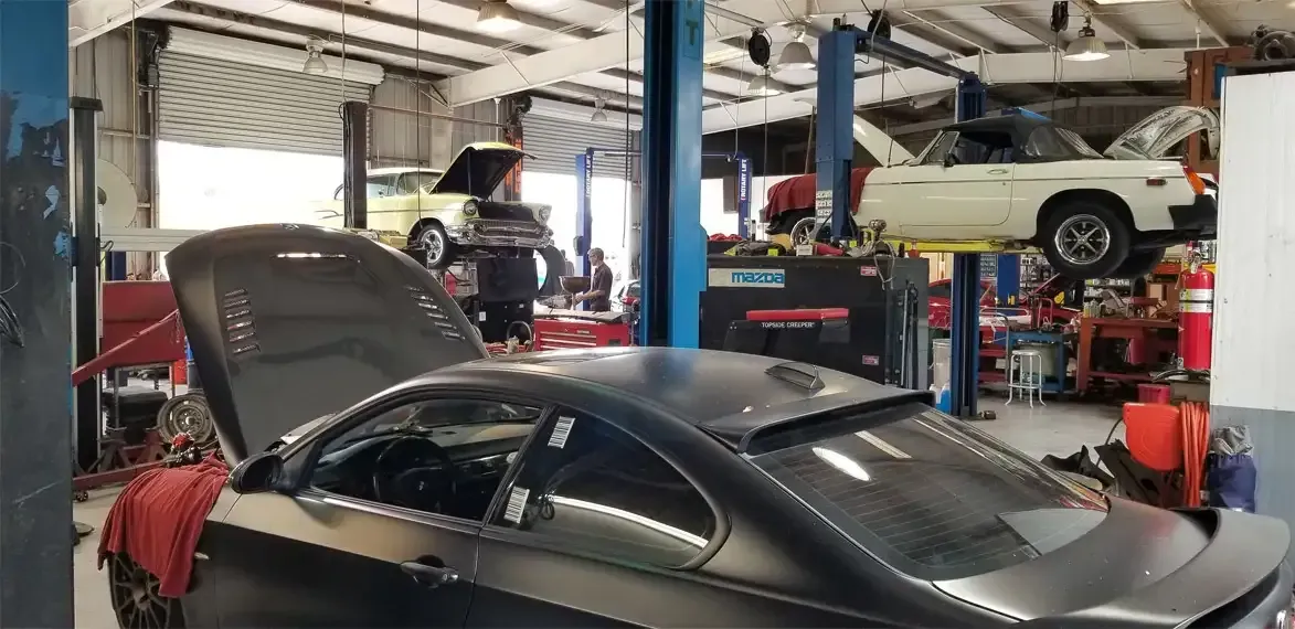 A car repair shop with several cars on lifts; one car has an open hood.