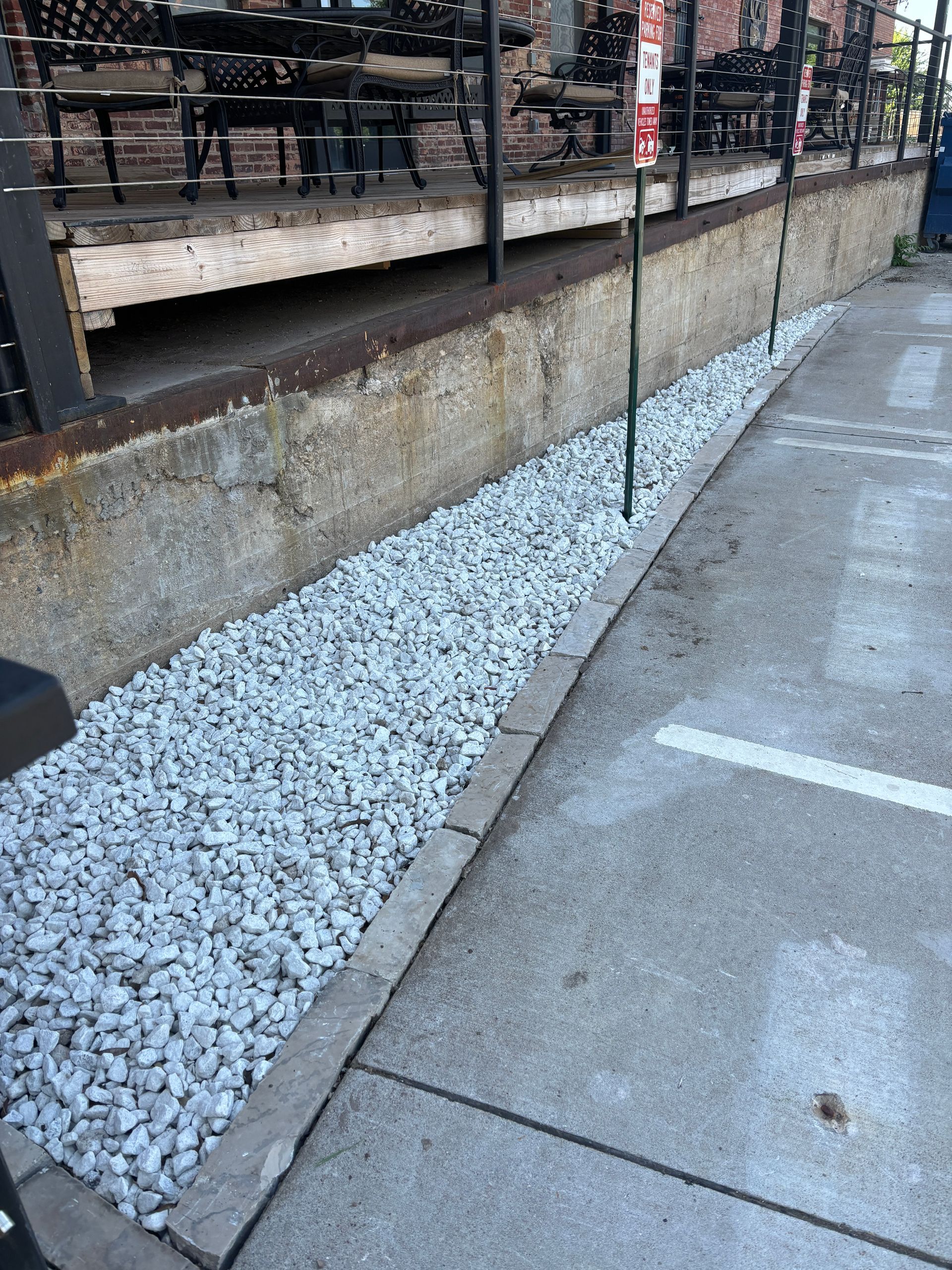 A sidewalk with white gravel and a no parking sign