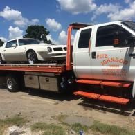 White car loaded on a tow truck by Pete Johnson Towing. Sunny day setting.