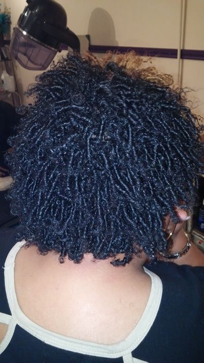 A woman with dreadlocks is sitting in front of a hair dryer.