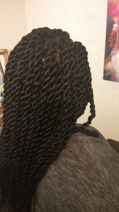 A woman with braids in her hair is sitting in a room.