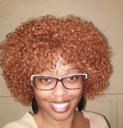A woman with curly hair and glasses smiles for the camera