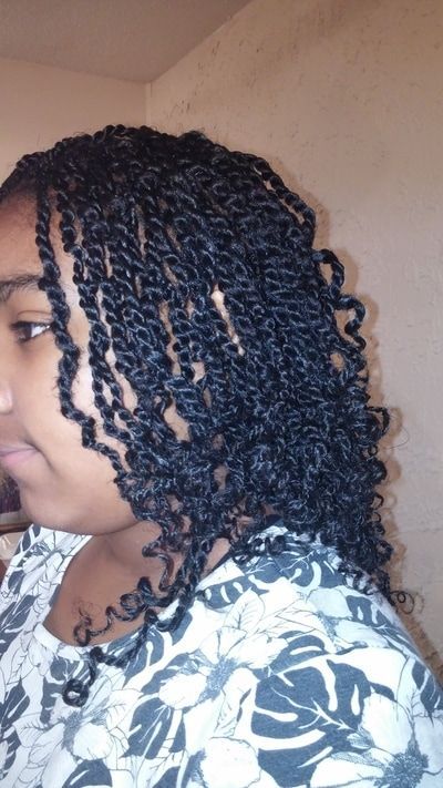 A woman with braided hair is wearing a floral shirt