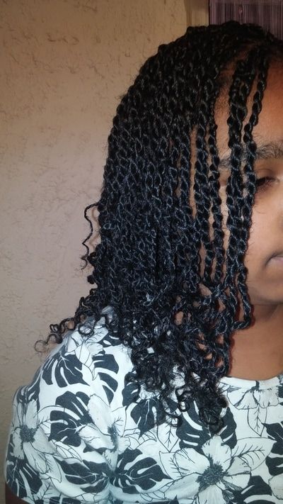 A woman with braids in her hair is wearing a floral shirt.