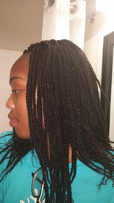 A woman with braids is wearing a blue shirt and glasses.