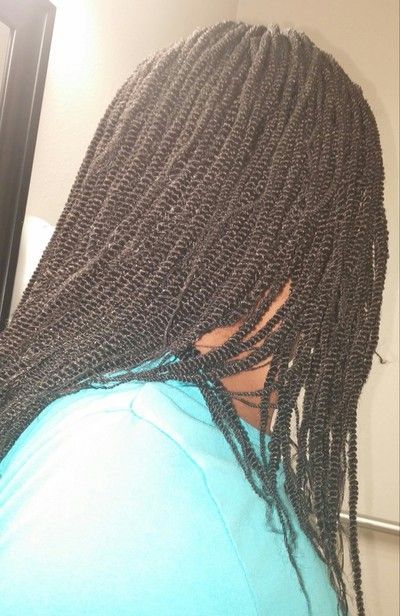 A woman with braids in her hair is looking at herself in the mirror.