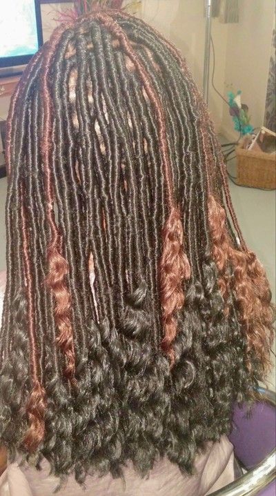 A woman with dreadlocks and curly hair is sitting in a chair.