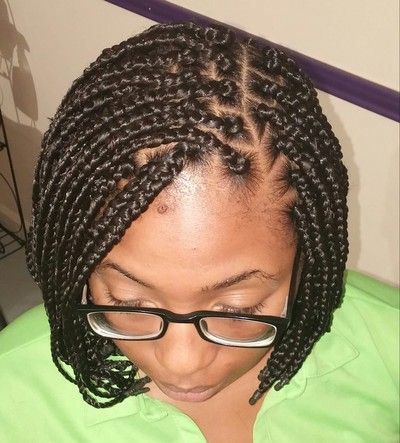 A woman with braids and glasses is wearing a green shirt