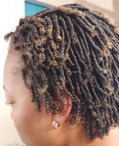 A close up of a woman 's hair with dreadlocks and earrings