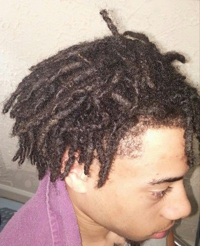 A man with dreadlocks is wearing a purple shirt.