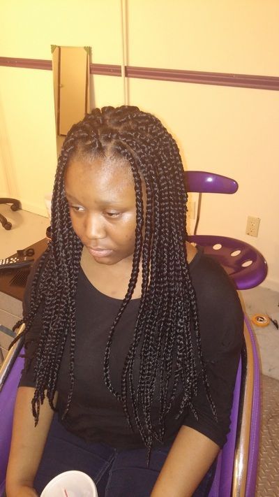 A woman with braids is sitting in a chair holding a cup of coffee.