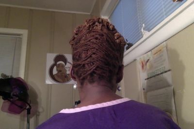 A woman in a purple shirt has her hair in a bun