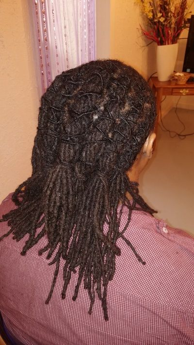 A woman with dreadlocks is wearing a purple shirt and headphones.