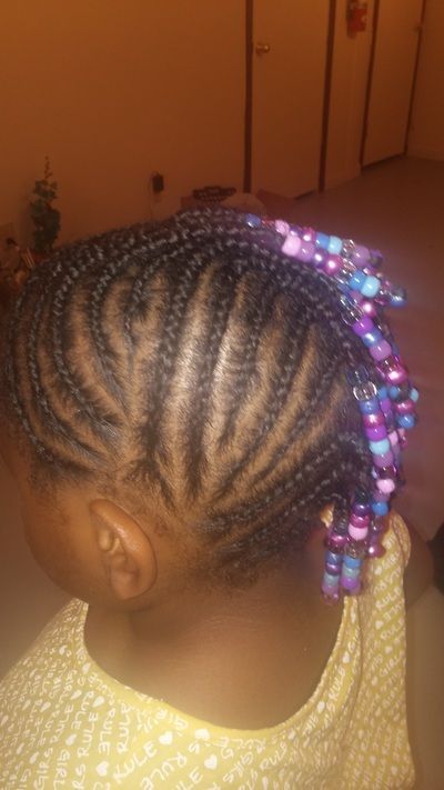 A little girl with braids and beads in her hair.