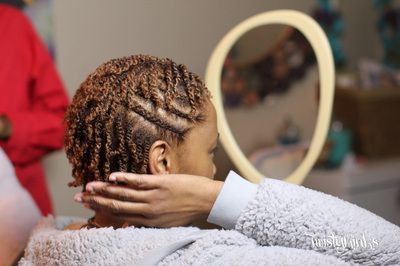 A woman is looking at her hair in a mirror.