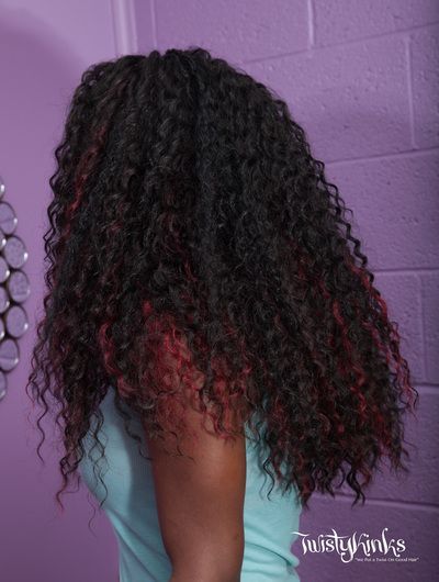 A woman with long curly hair is standing in front of a purple wall.