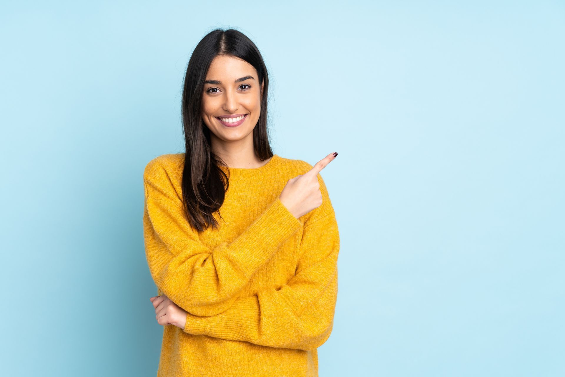 A woman in a yellow sweater is pointing to the side.