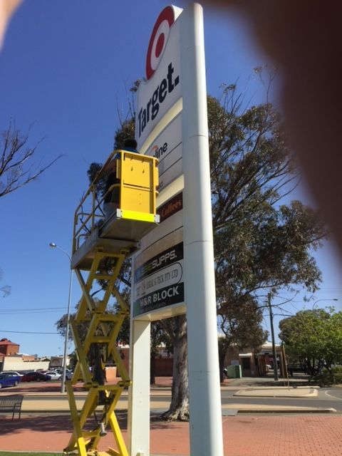 A target sign is being installed on a yellow lift