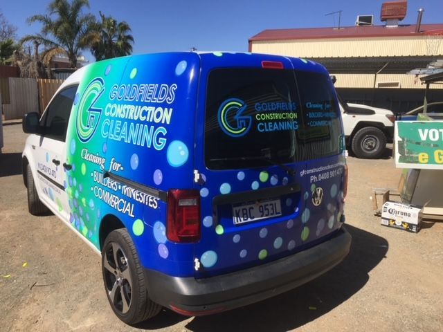 A blue and white van for construction cleaning is parked in a parking lot.