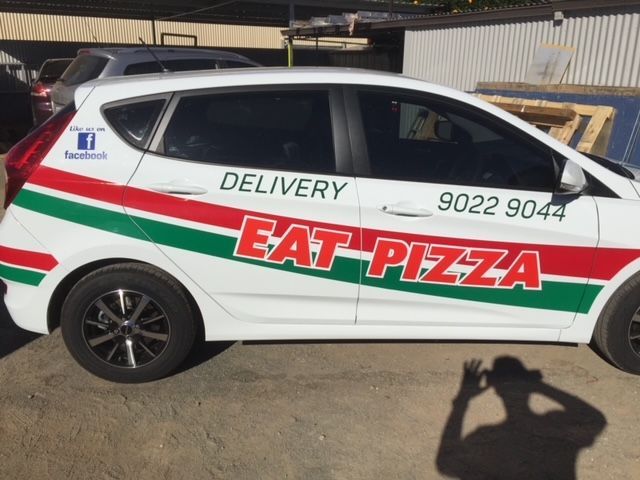A white car that says eat pizza on the side