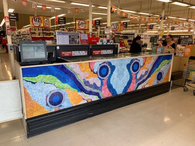 A grocery store cash register with a colorful painting on it
