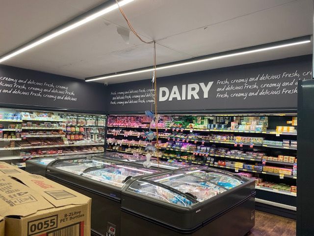 A dairy section of a grocery store with lots of freezers.